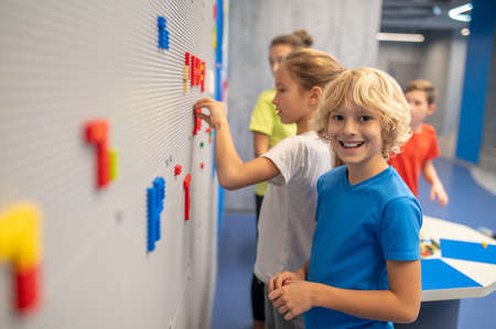 Boy smiling at camera playing lego with friendsの写真素材