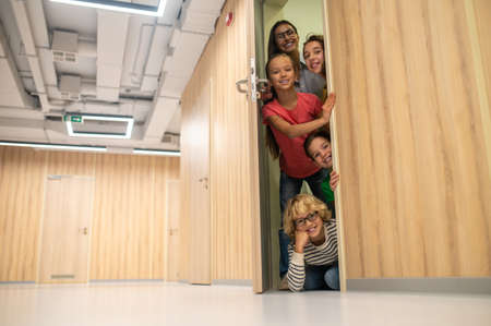 Happy kids with woman opening door looking at cameraの写真素材