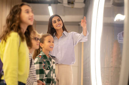 Teacher pointing to side and smiling children watchingの写真素材