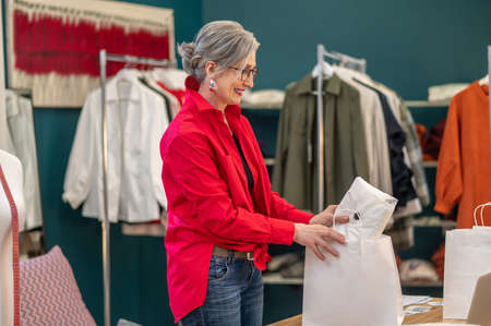 Woman putting clothes into package sideways to cameraの写真素材