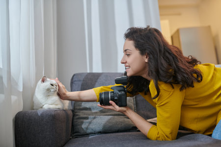 Pretty dark-haired woman with camera stroking her white cat