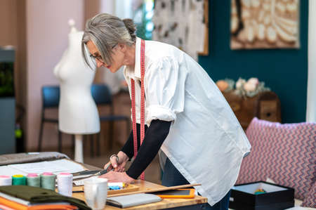 Woman tailor cutting pattern in atelierの写真素材