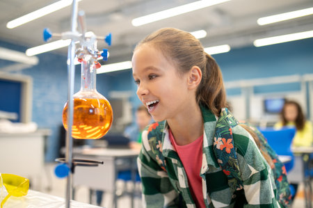 Girl with delight looking at flask in chemistry classの写真素材