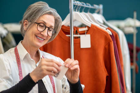 Woman hanging price tag on drawstringの写真素材