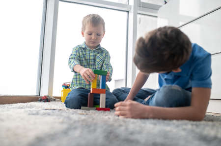 Two boys playing with toy blocks in a roomの写真素材