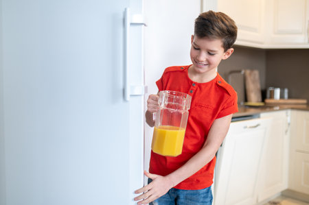 Smiling pleased boy closing the fridge doorの写真素材