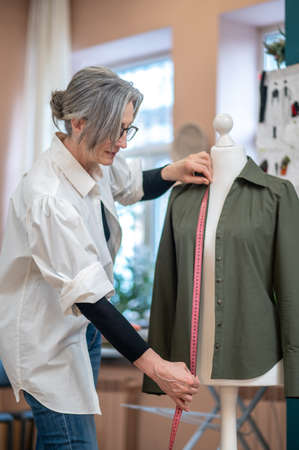 Woman touching blouse with measure on dummyの写真素材