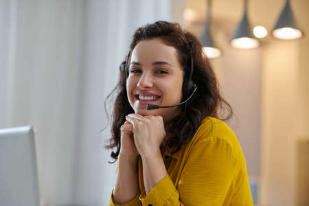 Dark-haired woman in a mustard shirt smiling nicelyの写真素材