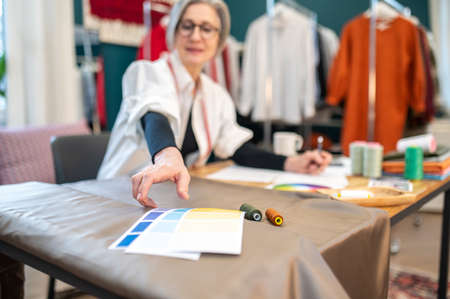 Woman at table stretching hand with color palettes