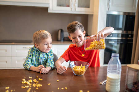 Kid watching his sibling making breakfast in the kitchen