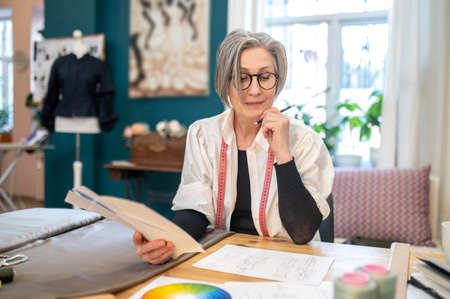 Woman sitting at table looking at sketchの写真素材