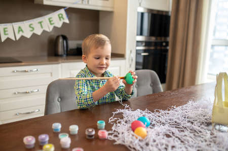 Focused creative boy decorating eggs for Easter