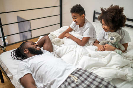 Father lying telling and interested listening childrenの写真素材