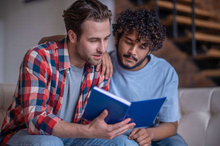 Two men involved in reading a bookの写真素材