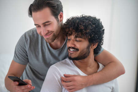 Pleased guy taking photos with his boyfriendの写真素材