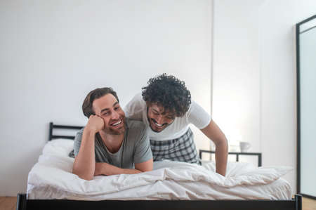 Happy gay couple lying on the duvetの写真素材