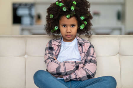 African american girl looking at camera sitting on sofaの写真素材