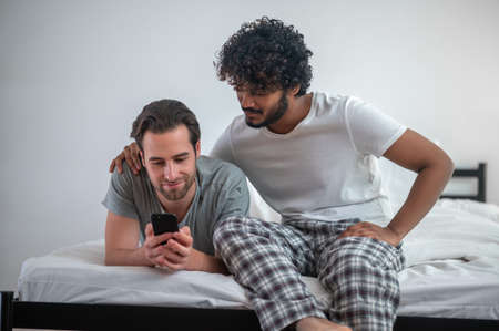Concentrated gay couple viewing selfies on the cellphone