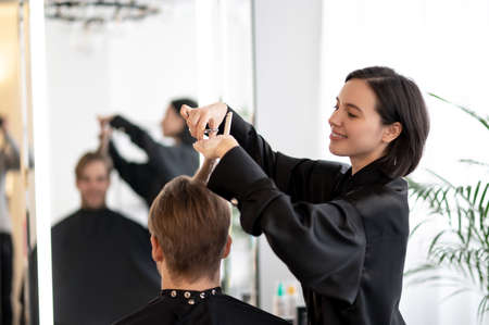 Dark-haired hairdresser working on a stylish haircutの写真素材