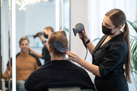 Hairdresser woring with the client in a beauty salon and looking involvedの写真素材