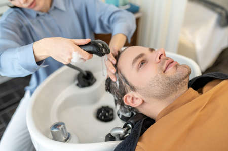 Hairdresser washing hair to the male client in a beauty salonの写真素材