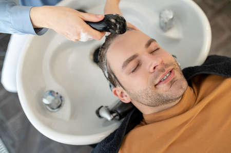 Hairdresser washing hair to the male client in a beauty salonの写真素材