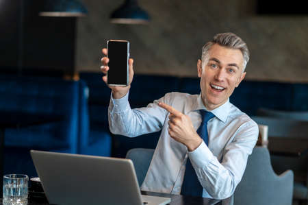 A smiling businessman showing his device and smiling