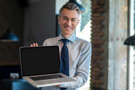 A smiling businessman showing his device and smiling