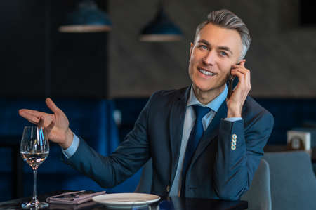 A good-looking businessman talking on the phone and looking contented
