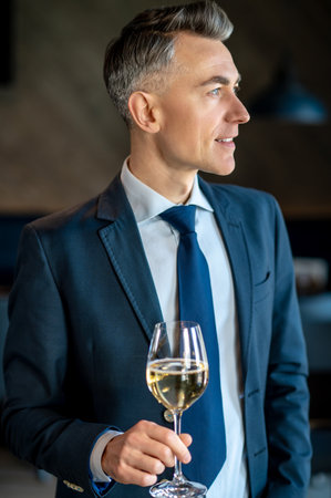 An elegant man in a suit with a glass of wine in handsの写真素材