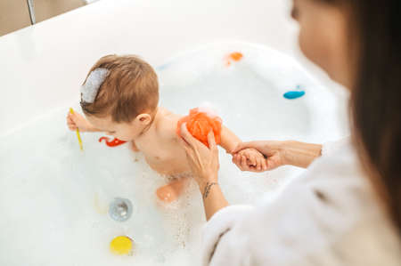 Woman washing her child seated in the bath