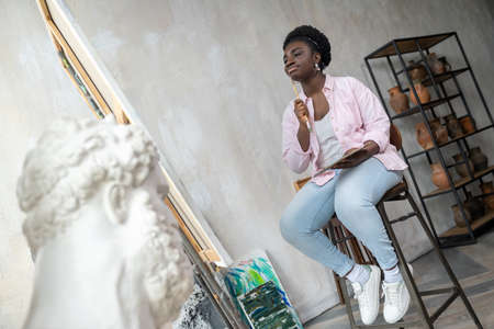 Contented african artist in pink clothes looking inspired