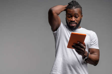 Shocked male looking at something on his gadgetの写真素材