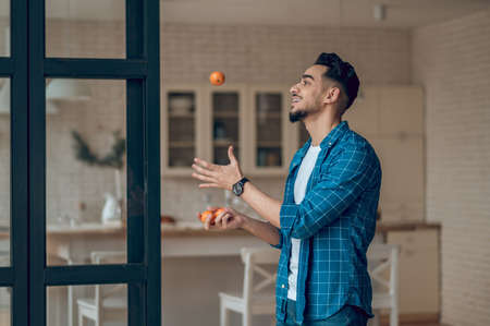 Young man in a blue tshirt juggling mandarinesの写真素材
