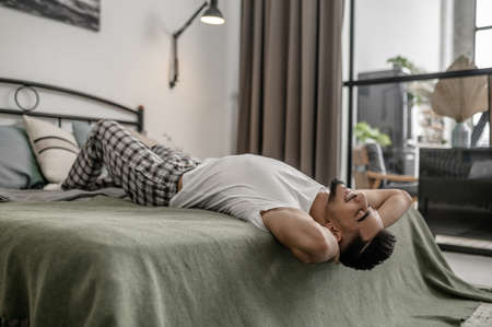 A man lying on the bed abnd looking relaxedの写真素材