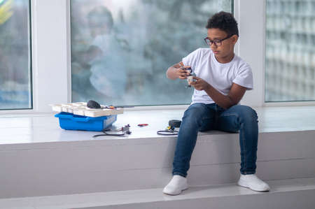 A dark-skinned boy constructing a transformer and looking busy