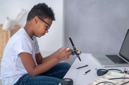 A dark-skinned boy constructing a transformer and looking busy