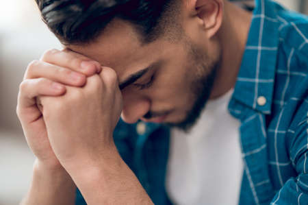 Young dark-haired man sitting with an unhappy look