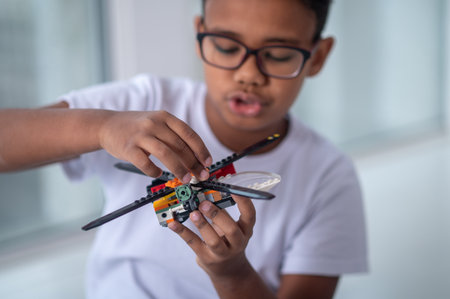 A boy in eyeglasses playing with a toy helicopter