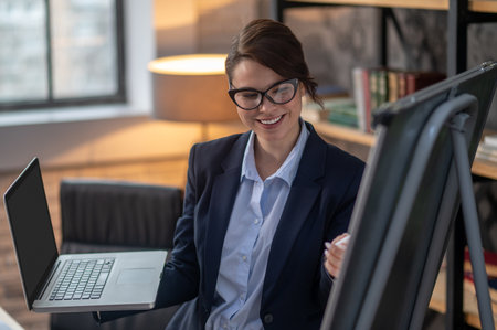 Elegant dark-haired woman presenting something to online audienceの写真素材