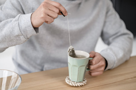 A man in a grey hoodie having tea