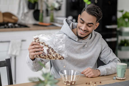 A smiling man in a grey hoodie making breakfast