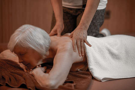 A senior woman having back massage in a beauty salonの写真素材