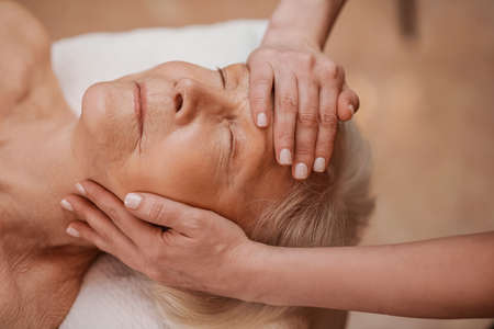 A senior woman having a face massage in a beauty salonの写真素材