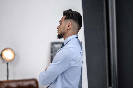 A stylish businessman in a blue shirt and tie standingの写真素材