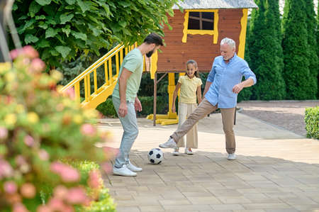 Family playing football in the park and looking involved
