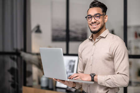 A young businessman with a laptop looking cotented