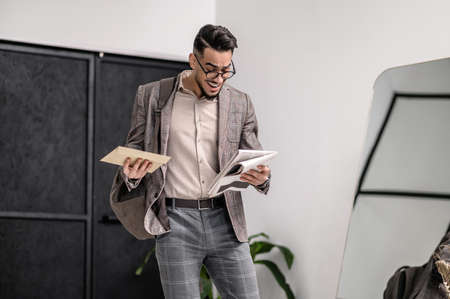 A man in a stylish jacket with some papers in handsの写真素材
