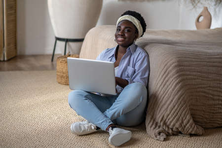 African american woman chatting on internet and looking interestedの写真素材