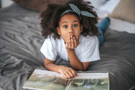 A sweet girl showing silence sign and looking excitedの写真素材